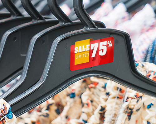 A red and orange colour sticker which stated “Sale limited 75%” is placed on a black colour cloth hanger.