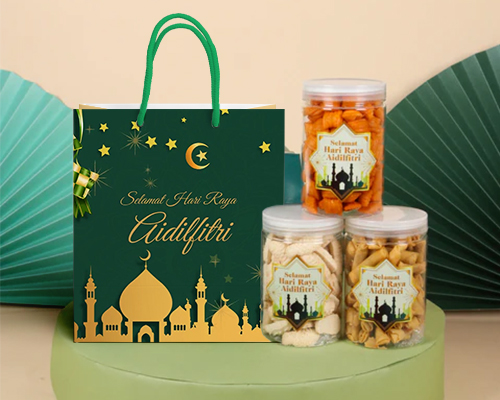 A green-coloured Raya paper bag with a matching green rope, alongside three bottles of Raya biscuits labelled Selamat Hari Raya Aidilfitri.