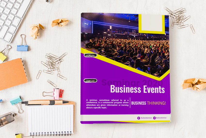 A purple arch file with a photo of a large crowd on the cover, labelled with “Seminar 2020 Business Events”, sitting next to an assortment of loose stationery.