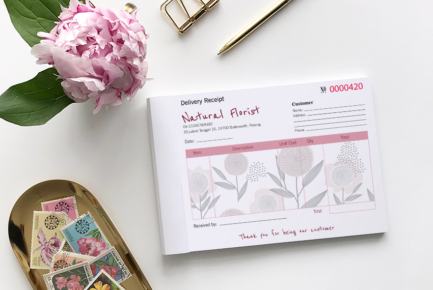 A receipt book decorated with a floral print next to a tray of stamps.