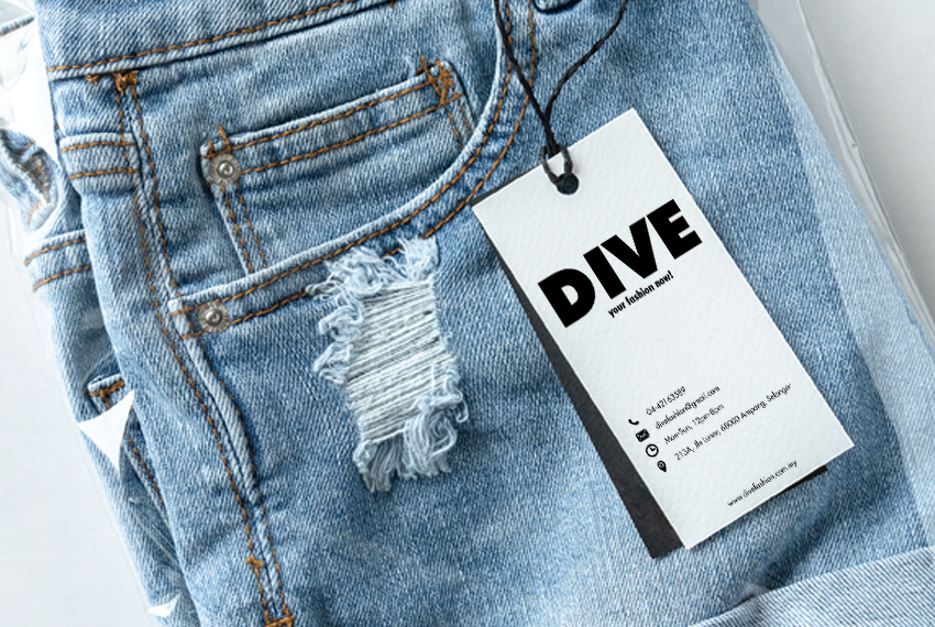 A clothing tag labelled “Dive” hanging from a pair of light blue, distressed jeans.