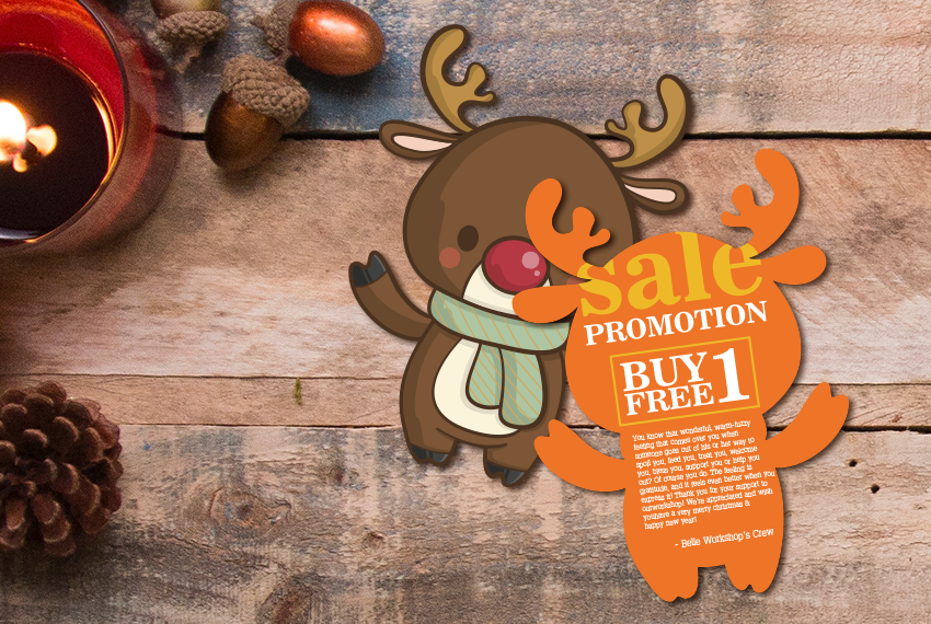 A card die-cut in the shape of a reindeer wearing a scarf. On the back side is printed promotional text highlighting a Buy One, Free One deal.