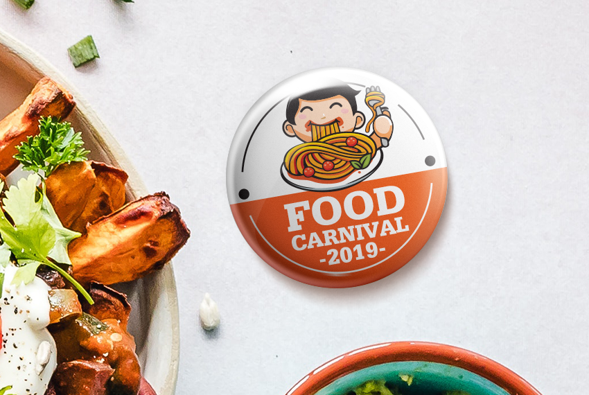 A button badge with a cartoon image of a man eating spaghetti labelled “Food Carnival 2019”.