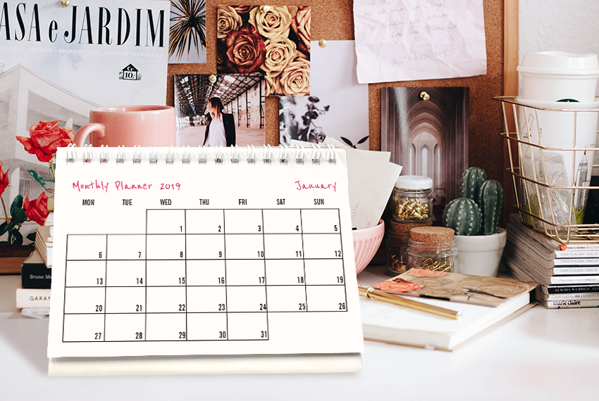 A simple soft stand desk calendar surrounded by several stationery and decor items.