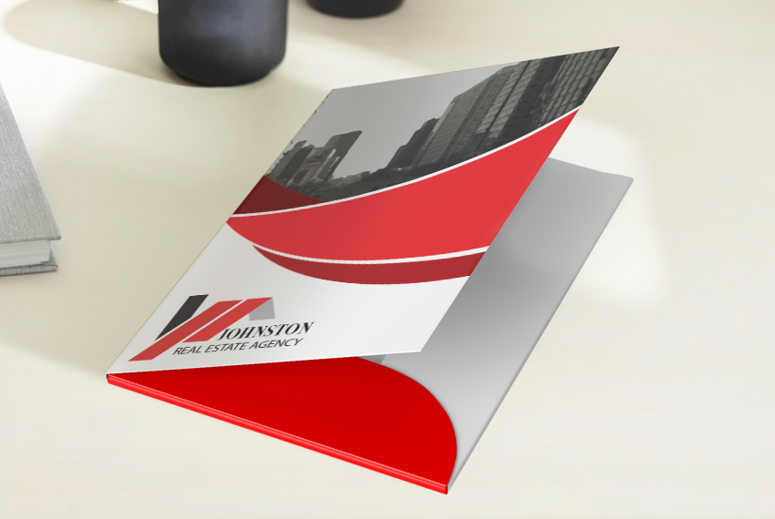 A red and white folder printed with a red swoosh design and a black-and-white photo of a city skyline.