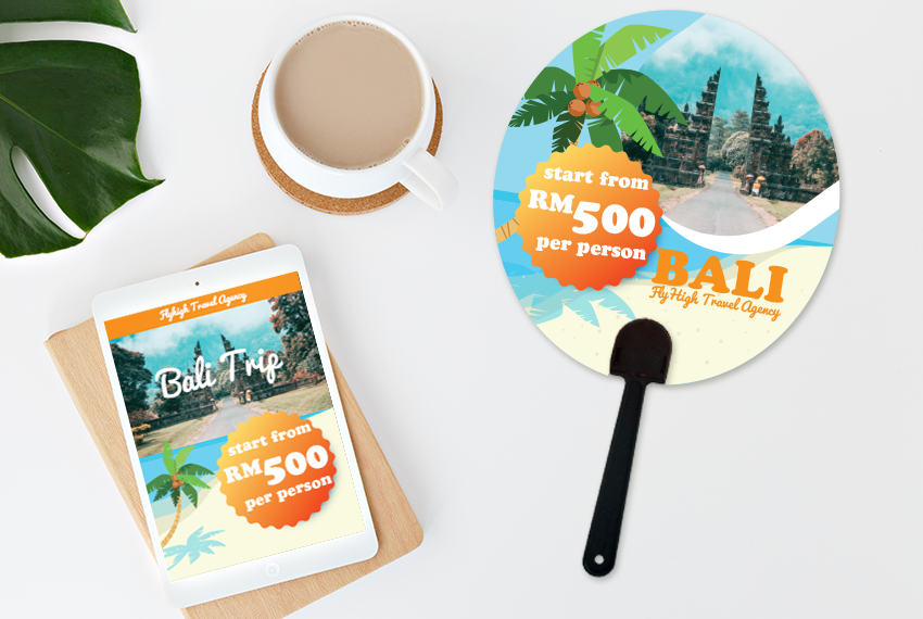 A circular hand fan advertising a travel package to Bali surrounded by a tablet and a cup of coffee.