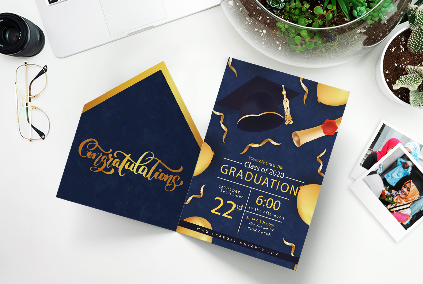 A card invitation to a graduation ceremony with a blue and gold design sit on a white surface.