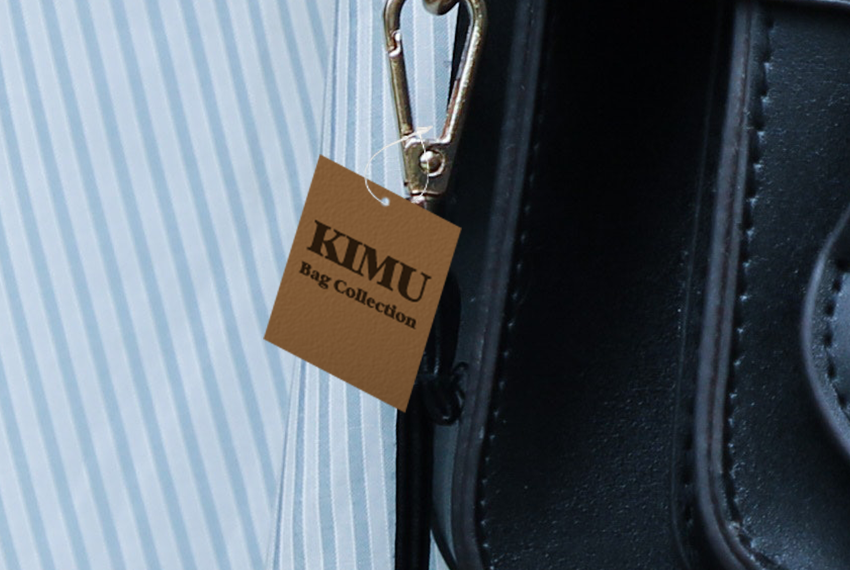 A tag that says “Kimu” hangs from the strap of a leather bag.