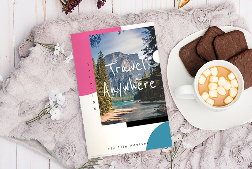 A plastic folder featuring an image of a mountain, and the words “Travel Anywhere” in white writing. Next to it is a platter of cookies and what appears to be hot cocoa with marshmallows.