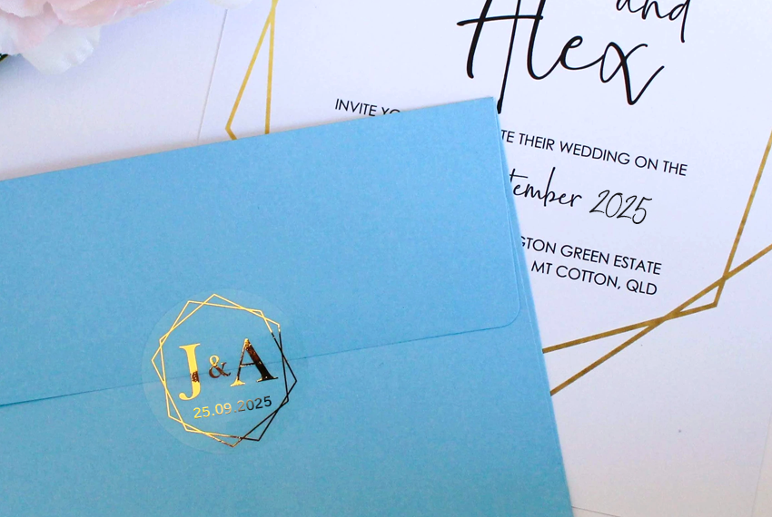 A blue envelope resting next to an invitation, sealed with a gold foil sticker.