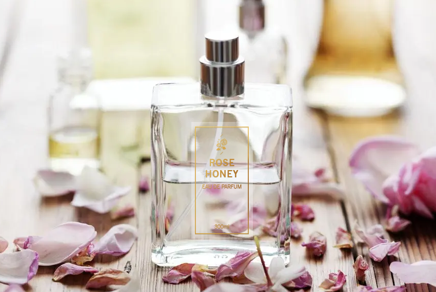 A perfume bottle with clear liquid is pasted with a gold foil sticker, and surrounded by loose rose petals.