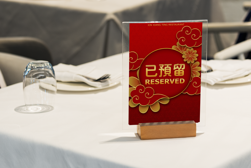A “Reserved” sign sits on a table for two covered in a white tablecloth.