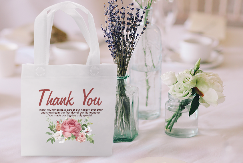 A tote bag that says “Thank You” sits in front of a glass vase holding lavenders.