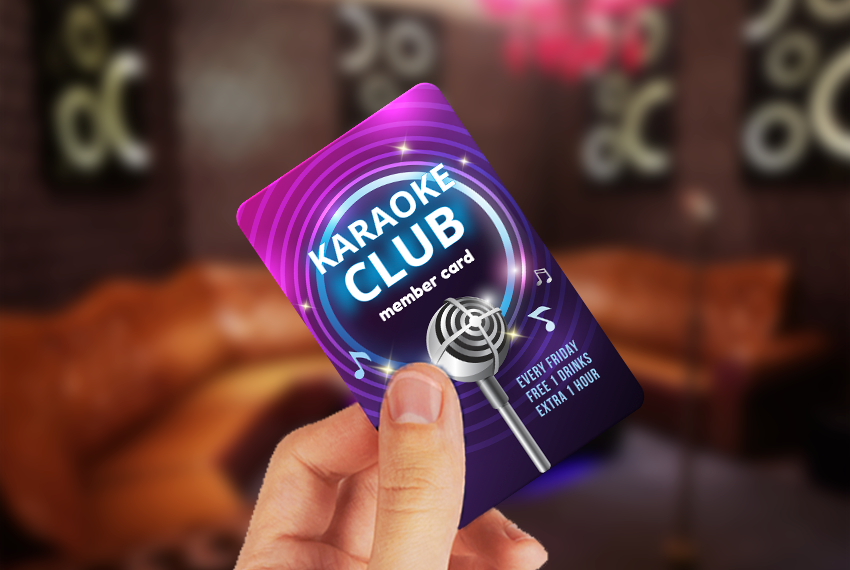 A hand holds onto a card that says “Karaoke Club” with a purple design.