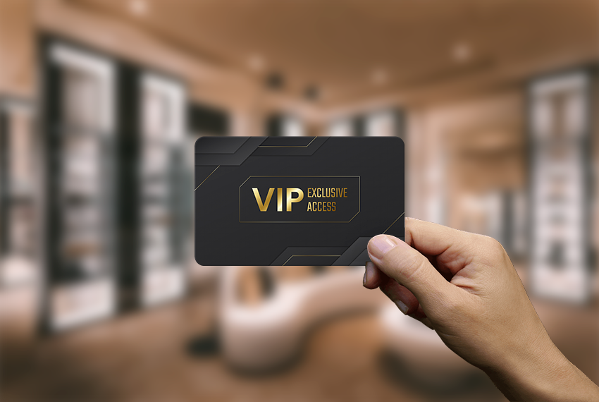 A hand holding onto a black card printed with gold lettering that says “VIP”.