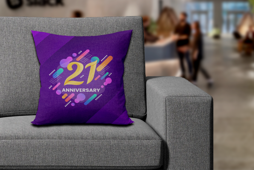A purple pillow sits on a sofa featuring the words “21 Anniversary”.