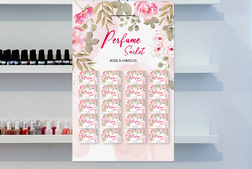 A pink sachet board hangs in front of a shelf, apparently holding perfume sachets.