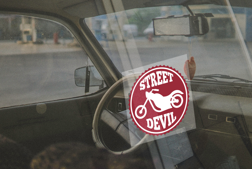 A window sticker in a car is printed with the image of a motorcycle and the text “Street Devil”.