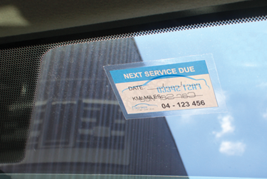 A window sticker featuring a reminder to when the next car service is.