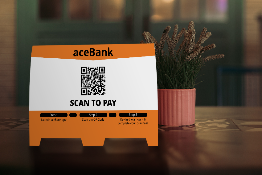 A tent card featuring a QR code to a bank, saying “Scan to Pay”.