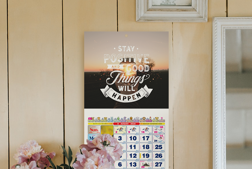 A wall calendar featuring an image of a sunset with the quote “Stay positive and good things will happen” printed across in large white text.