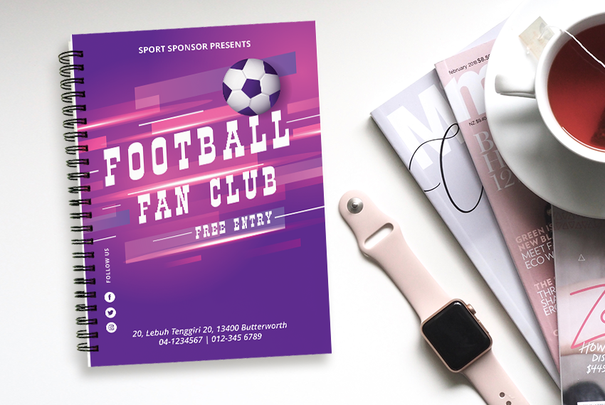A wirebound notebook with a purple design saying “Football Fan Club” sits next to a smartwatch and several magazines.