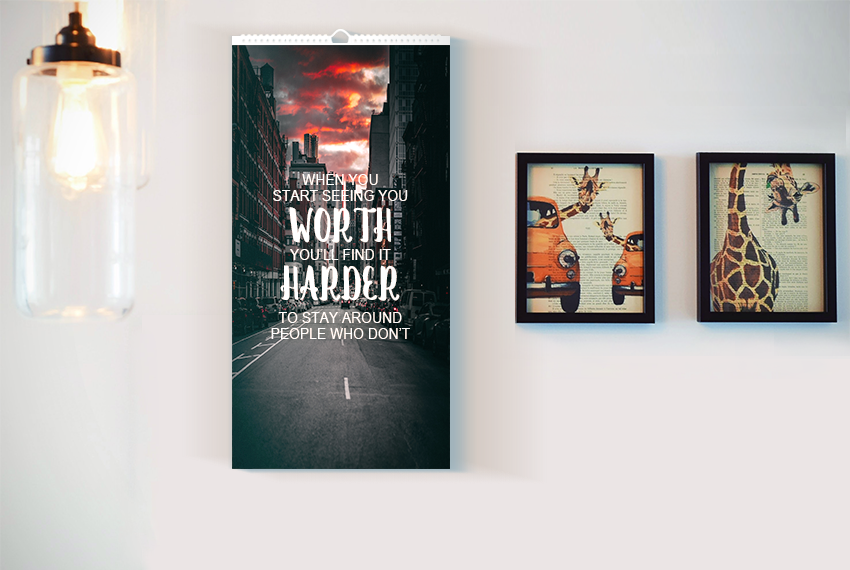 A wire-O bound wall calendar printed with a quote in white text over an image of a city at dusk.