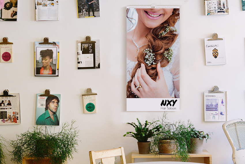 A wire-O bound wall calendar printed with the image of a woman holding her braid interwoven with several bunches of flowers, placed on a wall surrounded by several clipboards featuring other photographs.